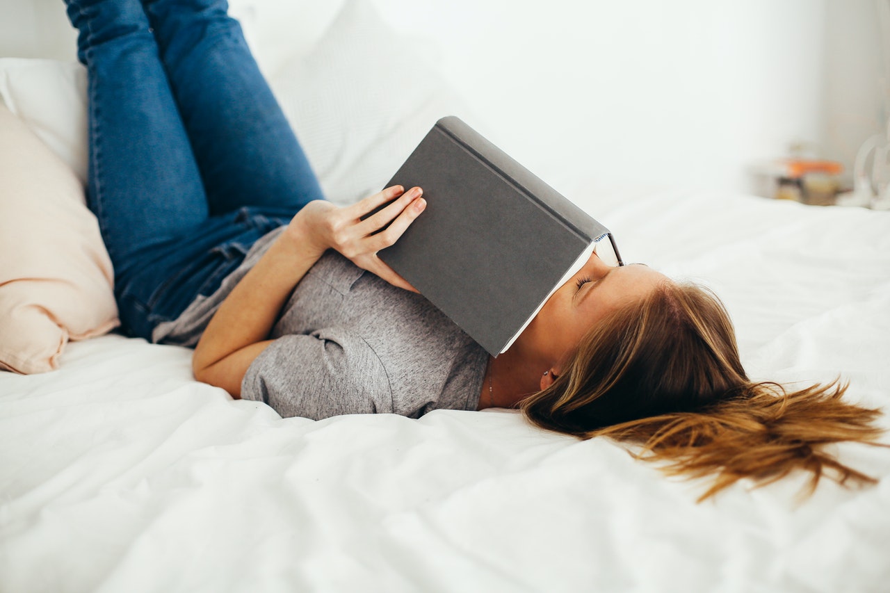 Kvinde læser bog i sin seng